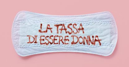 Un assorbente con la scritta "LA TASSA DI ESSERE DONNA" in rosso su sfondo rosa, che evidenzia il ciclo.