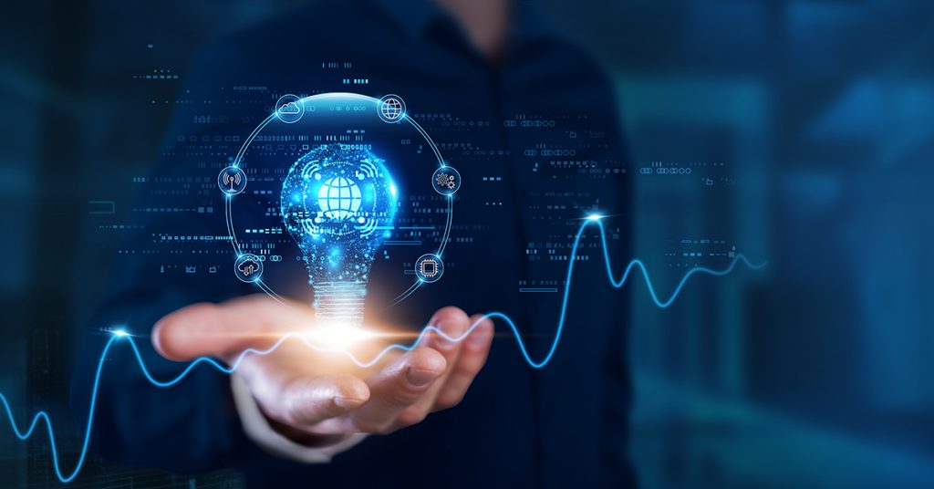 Una persona tende una mano con un ologramma di lampadina digitale, simbolo di innovazione, tecnologia e intelligenza artificiale.